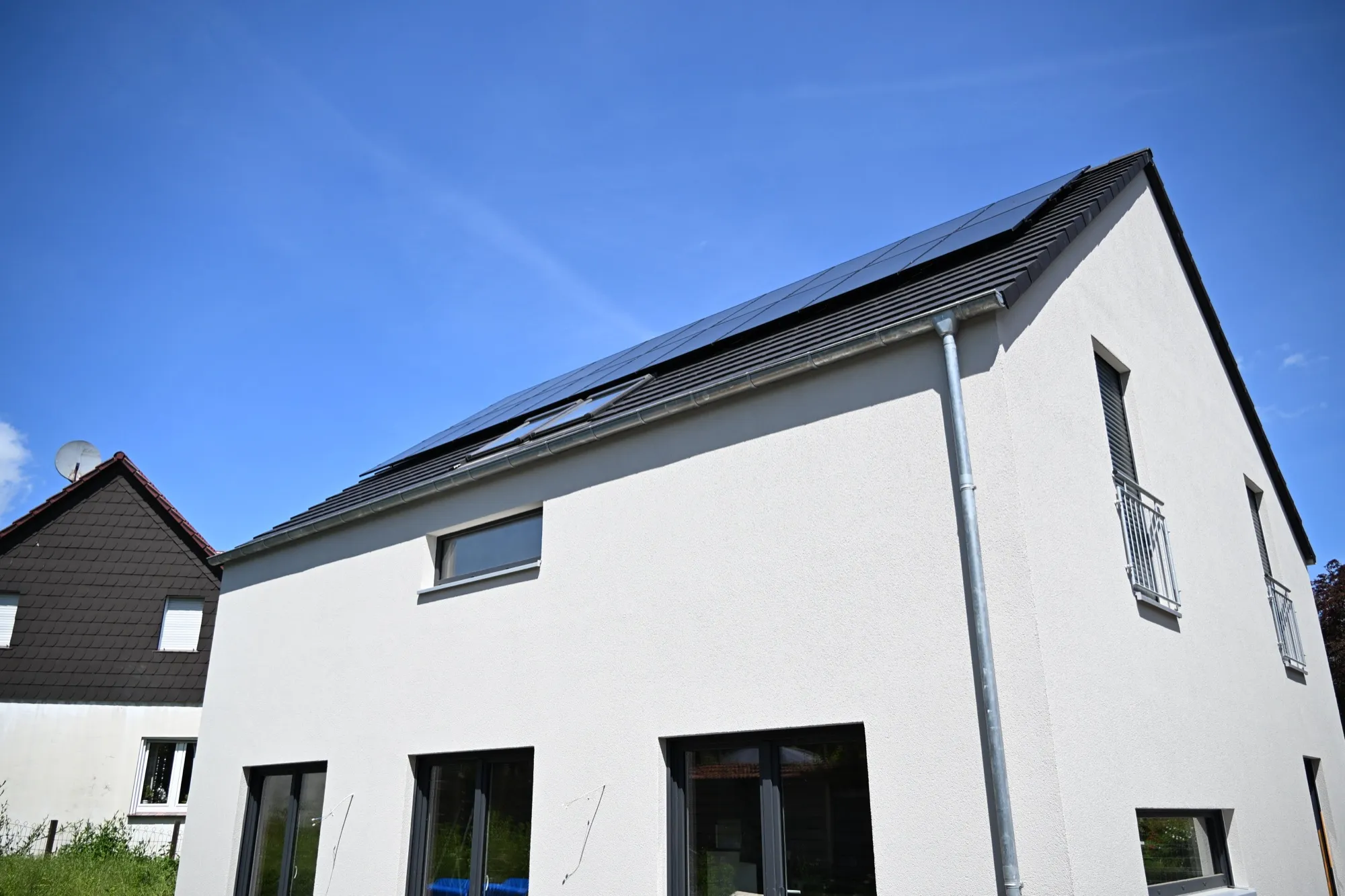 Modernes weißes Einfamilienhaus mit dunklem Satteldach und Photovoltaik, Neubauprojekt in Darup